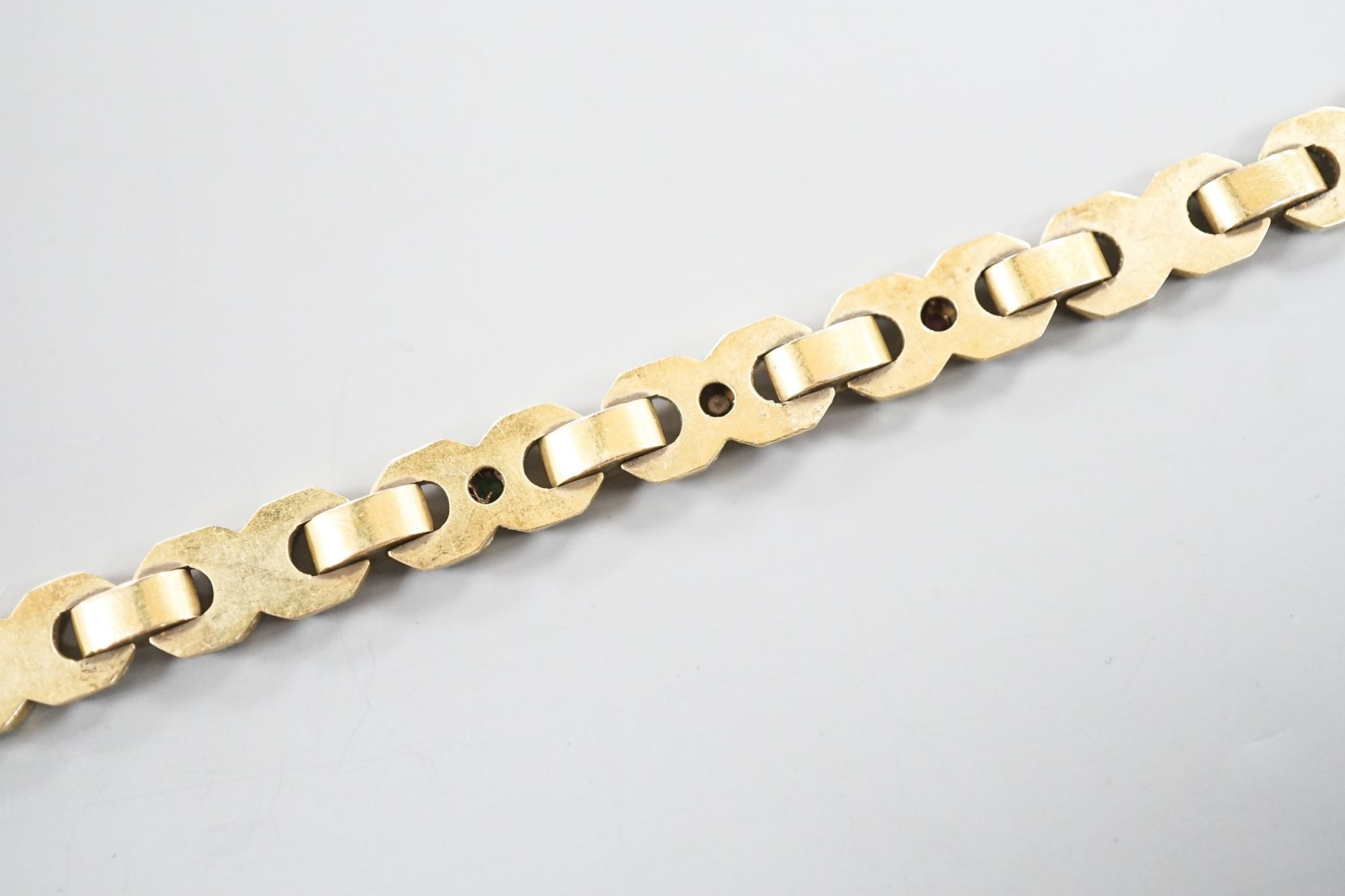 A modern continental yellow, metal, ruby, emerald and diamond set bracelet, 18.3cm, gross weight 14.5 grams.